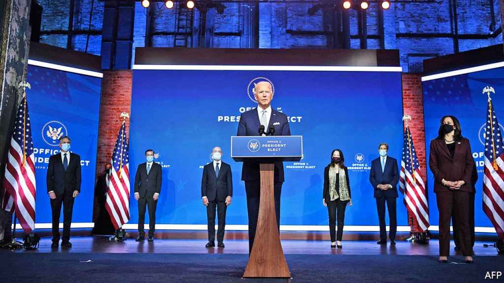 Joe Biden standing in a podium around people 
